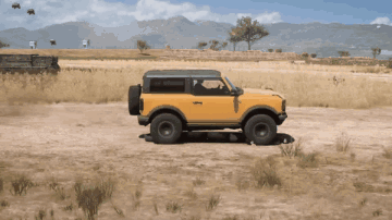 A Yellow Ford Bronco Is Driving Through A Desert GIF