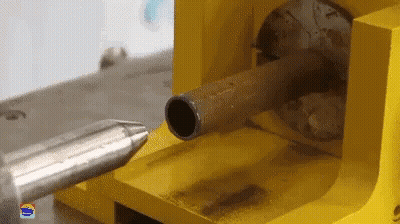 A Yellow Machine Is Cutting A Metal Pipe With A Needle GIF