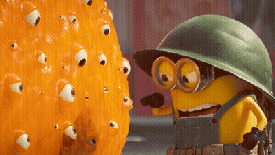 A Yellow Minion Wearing Overalls And A Helmet Is Pointing At An Orange Object With Eyes On It GIF