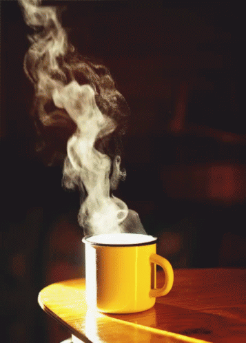 A Yellow Mug With Steam Coming Out Of It Sits On A Table GIF