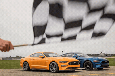A Yellow Mustang And A Blue Mustang Are Parked Next To A Checkered Flag GIF