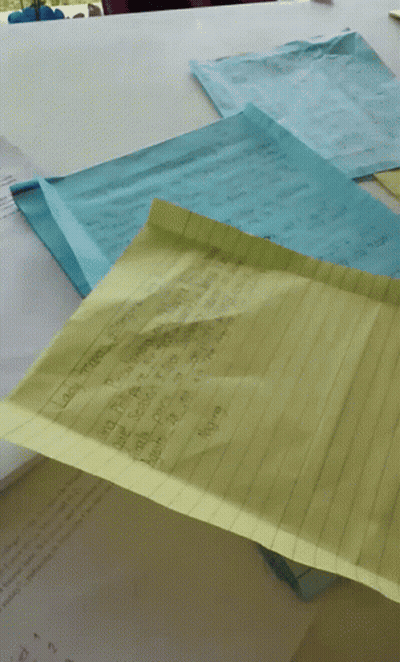 A Yellow Piece Of Paper Is Laying On Top Of A Pile Of Paper GIF