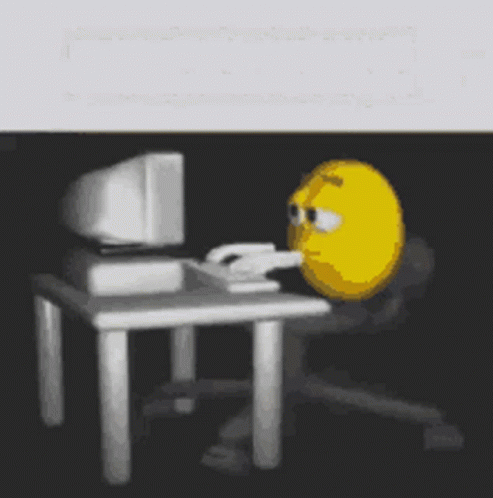 A Yellow Smiley Face Is Sitting In Front Of A Computer . GIF