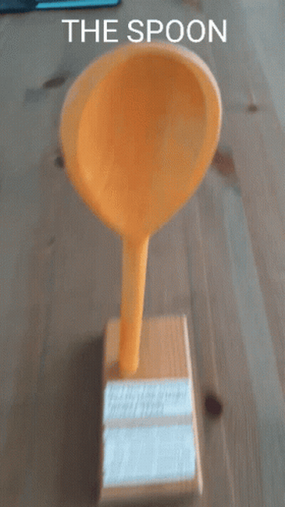 A Yellow Spoon Sitting On Top Of A Wooden Box With The Words " The Spoon " Below It GIF