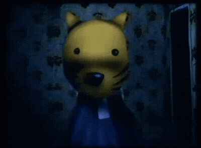 A Yellow Stuffed Animal With A Black Nose Is Standing In A Dark Room GIF