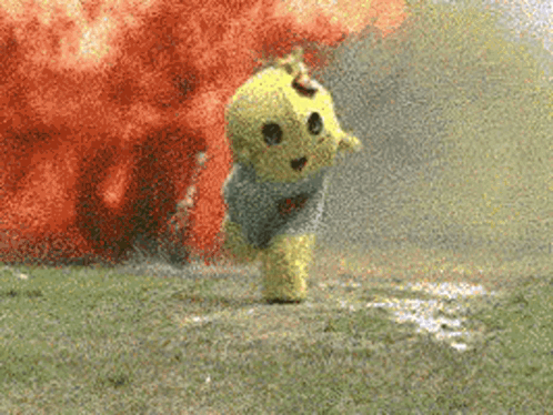 A Yellow Teddy Bear Is Running In Front Of An Explosion GIF