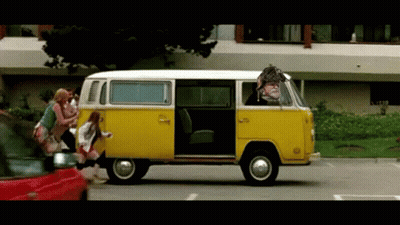 A Yellow Van With A Man In The Driver 'S Seat Is Driving Down The Street GIF