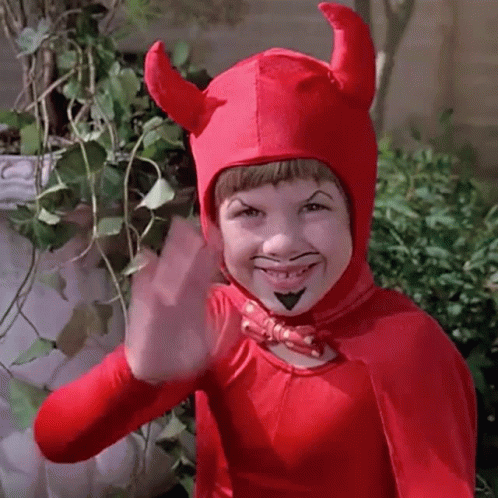 A Young Boy Dressed In A Devil Costume Is Waving . GIF