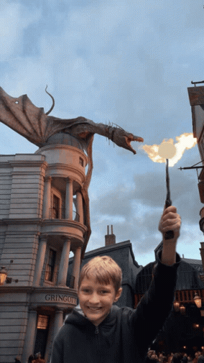 A Young Boy Holding A Wand In Front Of A Building That Says Gringotts GIF