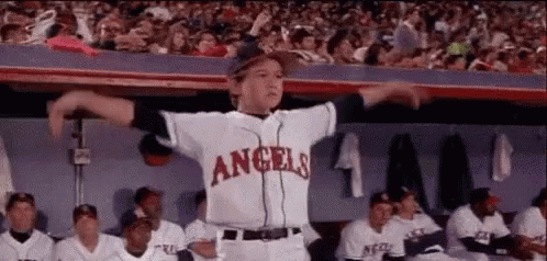 A Young Boy In A Baseball Uniform Is Dancing In The Dugout . GIF