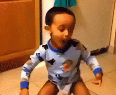 A Young Boy In A Blue And White Shirt Is Standing On A Toilet . GIF