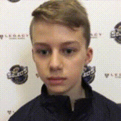 A Young Boy In A Blue Jacket Is Standing In Front Of A Wall With A Logo On It . GIF