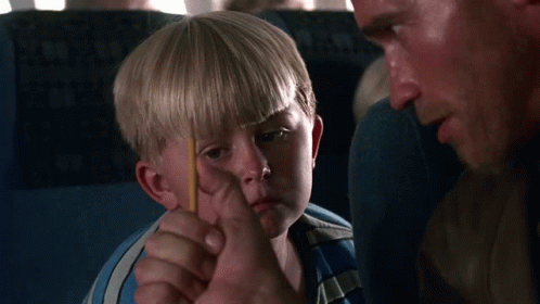 A Young Boy In A Blue Shirt Is Sitting On An Airplane GIF