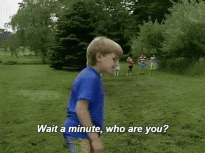 A Young Boy In A Blue Shirt Is Standing In A Grassy Field And Says " Wait A Minute Who Are You " GIF