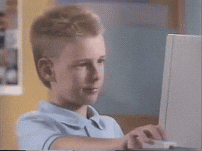 A Young Boy In A Blue Shirt Is Using A Laptop Computer GIF