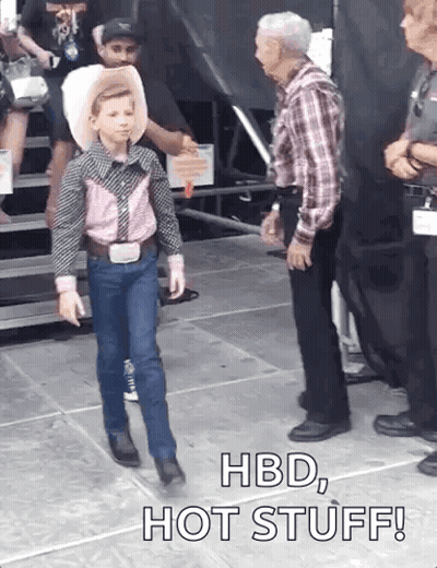 A Young Boy In A Cowboy Outfit Is Walking In Front Of A Man With The Words Hbd Hot Stuff Written On The Ground GIF