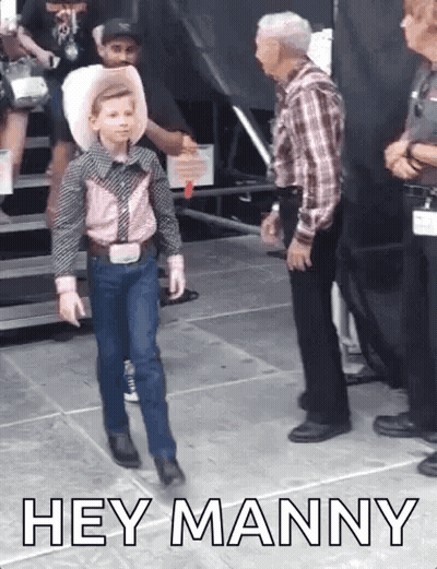 A Young Boy In A Cowboy Outfit Is Walking In Front Of A Man . GIF