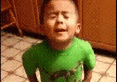 A Young Boy In A Green Shirt Is Standing On A Tiled Floor . GIF