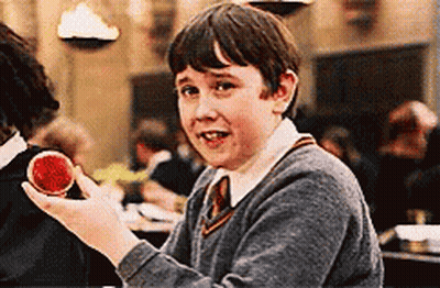 A Young Boy In A Harry Potter Uniform Is Holding A Red Object In His Hand . GIF