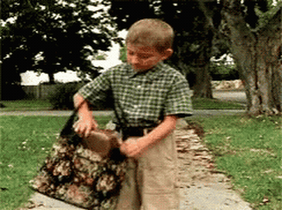 A Young Boy In A Plaid Shirt Is Holding A Large Bag GIF