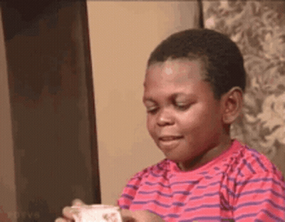 A Young Boy In A Red And Purple Striped Shirt Is Holding A Piece Of Paper In His Hand . GIF