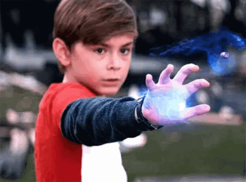 A Young Boy In A Red And White Shirt Is Holding Something In His Hand . GIF