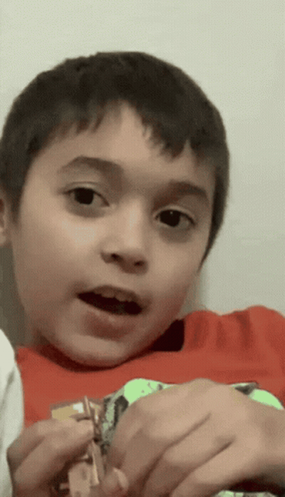 A Young Boy In A Red Shirt Is Holding A Toy GIF