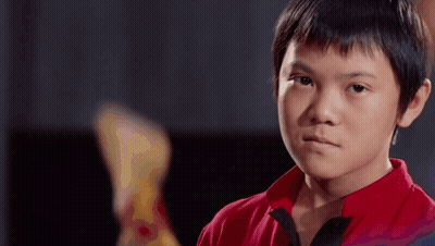 A Young Boy In A Red Shirt Is Looking At The Camera With A Serious Expression On His Face . GIF