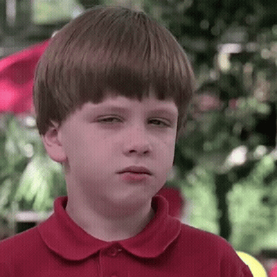 A Young Boy In A Red Shirt Is Making A Sad Face . GIF