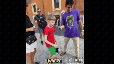 A Young Boy In A Red Shirt Is Standing Next To A Man In A Purple Shirt . GIF