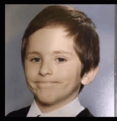A Young Boy In A Suit And Tie Is Making A Silly Face . GIF