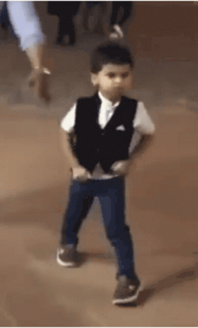 A Young Boy In A Suit And Vest Is Dancing On A Stage . GIF
