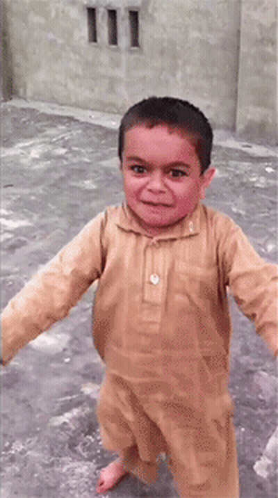 A Young Boy In A Tan Shirt Is Smiling And Walking GIF