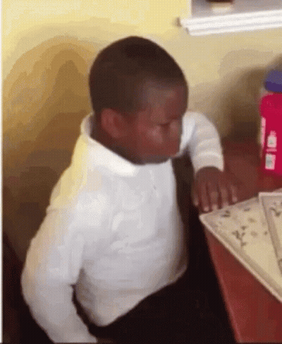A Young Boy In A White Shirt And Tie Is Sitting At A Table With His Eyes Closed . GIF