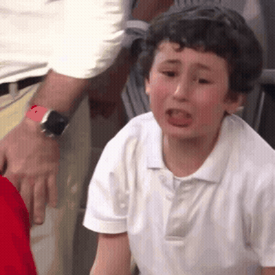 A Young Boy In A White Shirt Is Crying While A Man Holds His Arm . GIF