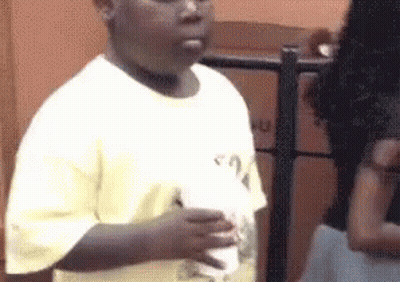A Young Boy In A White Shirt Is Holding A Cup Of Milkshake . GIF