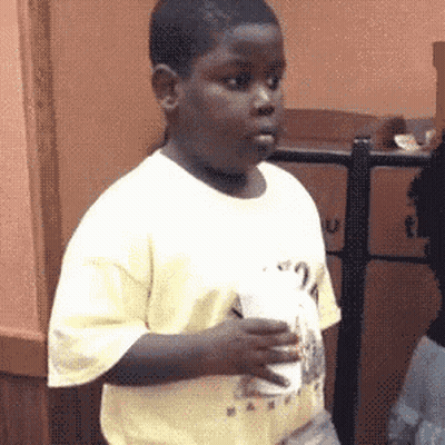 A Young Boy In A Yellow Shirt Is Holding A Cup Of Coffee . GIF