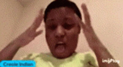 A Young Boy In A Yellow Shirt Is Making A Funny Face With His Hands On His Forehead . GIF
