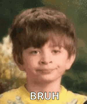 A Young Boy In A Yellow Shirt Is Smiling And Making A Face . GIF