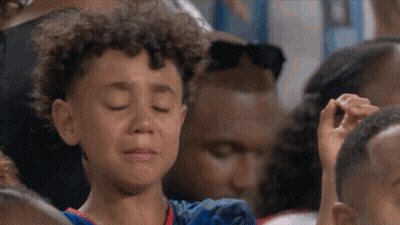 A Young Boy Is Crying In A Crowd Of People At A Sports Game . GIF