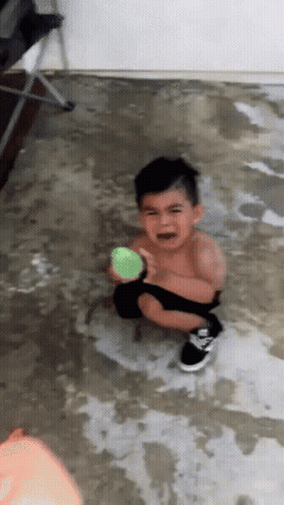 A Young Boy Is Crying While Holding A Ball GIF