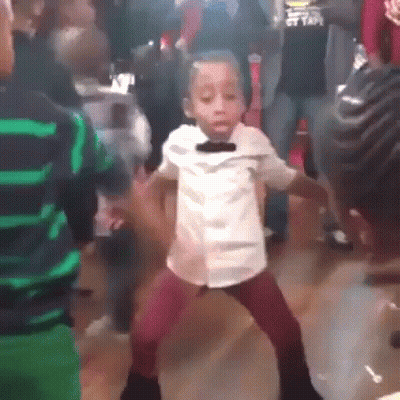 A Young Boy Is Dancing In A Crowd Of People . GIF
