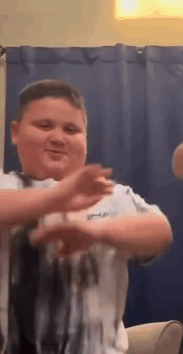 A Young Boy Is Dancing In A Living Room While Sitting On A Couch . GIF
