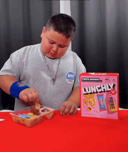 A Young Boy Is Eating A Box Of Lunchily Cereal GIF