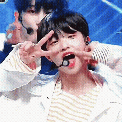 A Young Boy Is Giving A Peace Sign With His Tongue Out . GIF