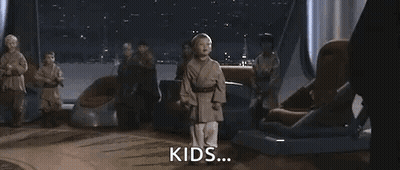 A Young Boy Is Holding A Blue Lightsaber In Front Of A Group Of People . GIF