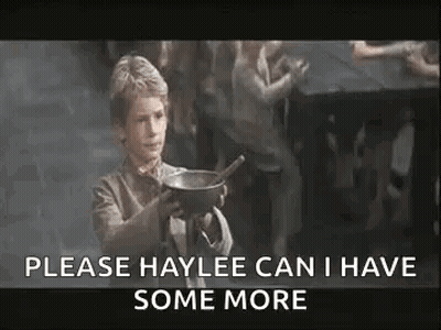 A Young Boy Is Holding A Bowl With A Spoon In It And Asking For Some More . GIF