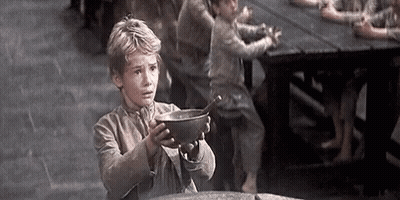 A Young Boy Is Holding A Bowl With A Spoon In It In Front Of A Group Of Children . GIF
