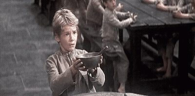 A Young Boy Is Holding A Bowl With A Spoon In It . GIF