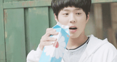 A Young Boy Is Holding A Carton Of Milk With A Flower Design On It GIF